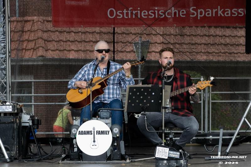 Zwei Musiker von Adams Family mit Gitarren auf der Bühne der Ostfriesischen Sparkasse.