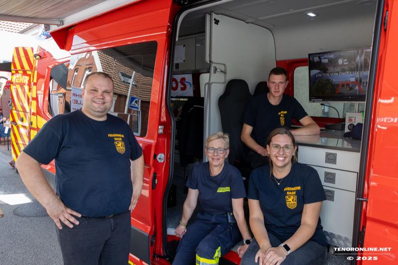 Vier Mitglieder der Freiwilligen Feuerwehr Hage an ihrem geöffneten Einsatzfahrzeug.